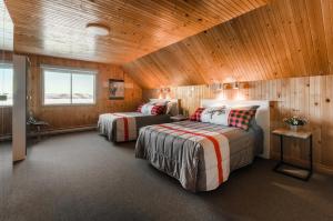 sypialnia z 2 łóżkami w pokoju z drewnianymi ścianami w obiekcie Auberge du Lac-à-l'Eau-Claire w mieście Saint-Alexis-des-Monts