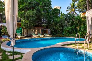 a swimming pool with chaise lounge chairs and a resort at Resort Martins Siesta , A Portuguese Heritage Resort in Calangute in Arpora