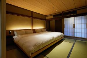 a bedroom with a large bed in a room with windows at UNO RETREAT Kyoto Gluten Free & Vegan Hotel in Kyoto