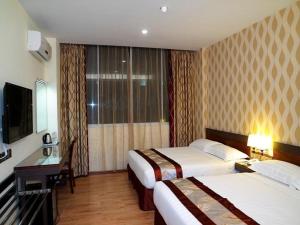 a hotel room with two beds and a television at Nova Kuching Hotel in Kuching