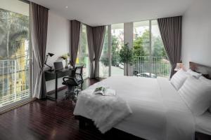 a bedroom with a large white bed and a balcony at Pegasy Suites Lakeside in Hanoi