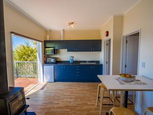cocina con armarios azules y mesa en That View - Kaiteriteri Holiday Home, en Kaiteriteri