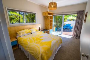 1 dormitorio con 1 cama con edredón amarillo y ventana en That View - Kaiteriteri Holiday Home, en Kaiteriteri