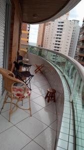 Un balcón con sillas y mesas en un edificio en Apartamento praia Grande en São Paulo
