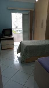 um quarto com uma cama e uma televisão num piso de azulejo em Apartamento praia Grande em São Paulo
