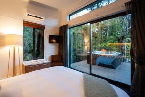 ein Schlafzimmer mit einem großen Fenster und einer Badewanne im Freien in der Unterkunft Rainforest Deluxe in Franz Josef