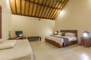 a bedroom with two beds and a tv in it at Rumi Villas in Seminyak