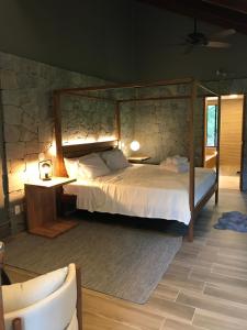 ein Schlafzimmer mit einem Bett und einer Steinmauer in der Unterkunft Chalé Realli in Visconde De Maua