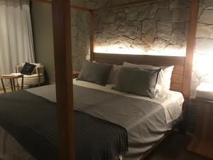 a bedroom with a bed with a stone wall at Chalé Realli in Visconde De Maua