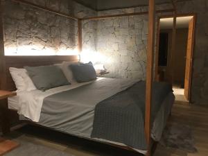 a bed in a room with a stone wall at Chalé Realli in Visconde De Maua