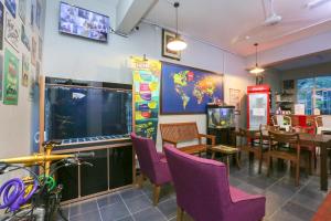 a restaurant with purple chairs and a large screen television at SPOT ON 89751 Bed Station Guest House in Tanah Rata