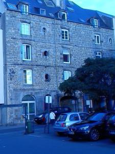 un grande edificio in pietra con macchine parcheggiate di fronte di Appartement Clémenceau a Saint Malo