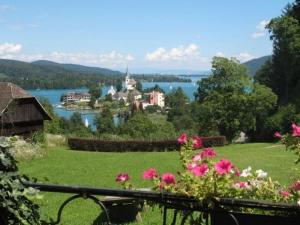 Blick auf die Stadt und einen See mit rosa Blumen in der Unterkunft Haus Edith in Maria Wörth