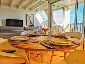 a wooden table with plates and wine glasses on it at Les Balcons de La Trinité - Vue sur mer et le port in La Trinité-sur-Mer +18 photos