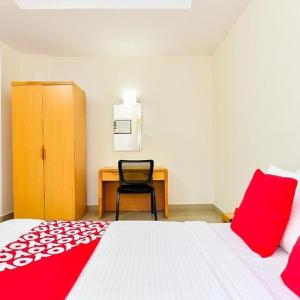 um quarto com uma cama com almofadas vermelhas e uma secretária em TRI-STAR RESIDENCY Cochin em Ernakulam