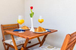 uma mesa de madeira com dois copos de sumo de laranja e uma flor em Apartment Amabilis em Mlini
