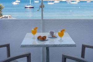 a table with a plate of food and two glasses of orange juice at Irene Hotel - Beachfront in Parikia