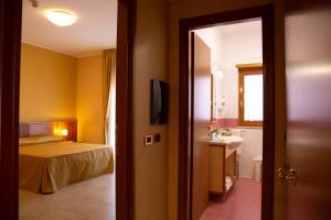 ein Schlafzimmer mit einem Bett und ein Badezimmer mit einem Waschbecken in der Unterkunft Hotel Maddaloni in Tufino