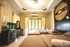 a bedroom with two beds and a tv and a window at Pai Panalee The Nature Boutique Hotel in Pai