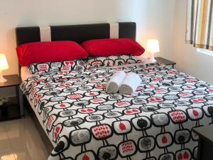 ein Bett mit einer schwarzen und roten Bettdecke und Kissen in der Unterkunft Menara U Shah Alam Guest House in Shah Alam