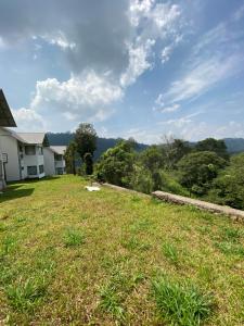 a large grassy yard with a house in the background at Mannoor Farms Mountain View Stays, Munnar in Munnar