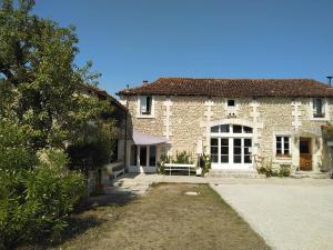 una gran casa de piedra con un banco frente a ella en La Grange de Lucie -chambres d'hôtes en Périgord-Dordogne, en Nanteuil-de-Bourzac