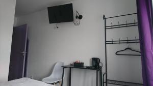 a bedroom with a table and a tv on the wall at Hôtel Les Deux Porches in Verrières