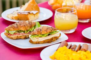 two sandwiches on white plates on a table with orange juice at Hotel Villa Sole Resort in Bellaria-Igea Marina