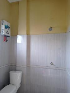 a bathroom with a toilet and a air conditioner on the wall at Kaesa Homestay in Berastagi