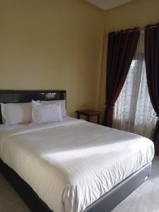 a large white bed in a bedroom with a window at Kaesa Homestay in Berastagi