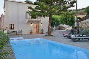 a blue swimming pool in front of a house at Villa Christini a luxury villa with amazing views in Tzitzifés