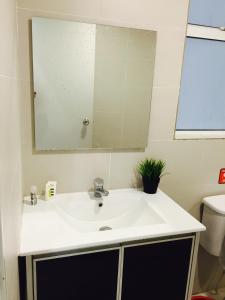 ein Badezimmer mit einem weißen Waschbecken und einem Spiegel in der Unterkunft Menara U Shah Alam Guest House in Shah Alam