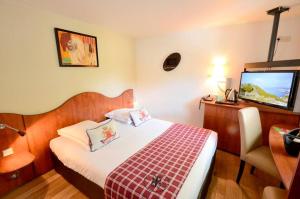 una camera d'albergo con letto e TV di Greenhotels Roissy Parc des Expositions a Tremblay-en-France