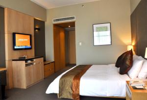 ein Hotelzimmer mit einem Bett und einem Flachbild-TV in der Unterkunft Jianguo Hotel Guangzhou in Guangzhou