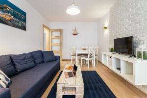 a living room with a blue couch and a table at Victus Apartamenty, Apartament Livia in Sopot