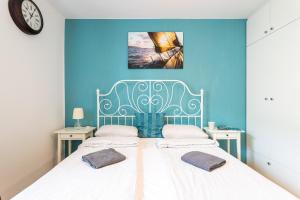 two beds in a room with blue walls and a clock at Victus Apartamenty, Apartament Livia in Sopot