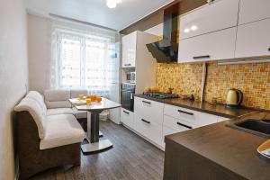 una cocina con armarios blancos y una mesa. en PaulMarie Apartments on Yunosti, en Mazyr