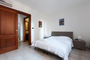 a bedroom with a white bed and a wooden door at Casa Giuseppe in Morciano di Leuca