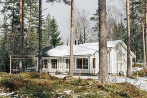 a white house with a snow covered roof in the woods at Katve Nature Retreat in Kirkkonummi