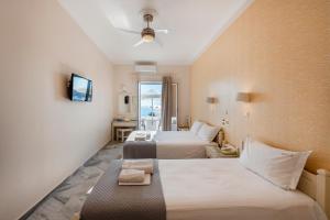 a hotel room with two beds and a television at Irene Studios - Beachfront in Parikia