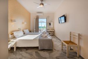 a bedroom with a large white bed and a television at Irene Studios - Beachfront in Parikia