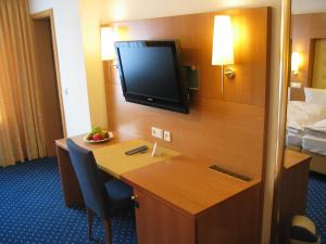 a hotel room with a desk with a television on the wall at Hotel-Restaurant-Kolb in Illertissen