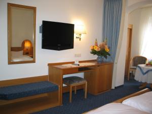a hotel room with a desk with a television on the wall at Hotel-Restaurant-Kolb in Illertissen