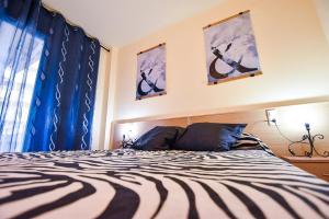 1 dormitorio con 1 cama con cortinas azules y ventana en Residencial Ventura Park / Royal / Jerez, en Salou