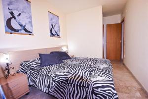 Una cama con estampado de cebra en una habitación blanca con en Residencial Ventura Park / Royal / Jerez, en Salou