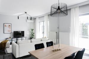 a living room with a white couch and a table at Spacious & Airy 1BR Apartment near HELEXPO Marousi by UPSTREET in Athens