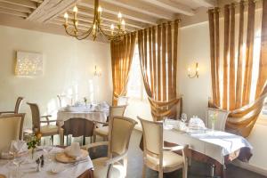 un restaurante con mesas y sillas blancas y una lámpara de araña en Logis Hôtel & Restaurant du Sauvage, en La Ferté-Gaucher