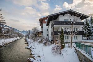 een huis in de sneeuw naast een rivier bij Chalet Wallner by AlpentTravel in Bad Hofgastein