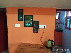 a room with an orange wall with pictures on it at MangalMurti Himalyan Homestay in Hawālbāgh