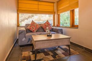 uma sala de estar com um sofá e uma mesa em Golden Bliss Cottage by VEO - Part of StayVista em Rāmgarh